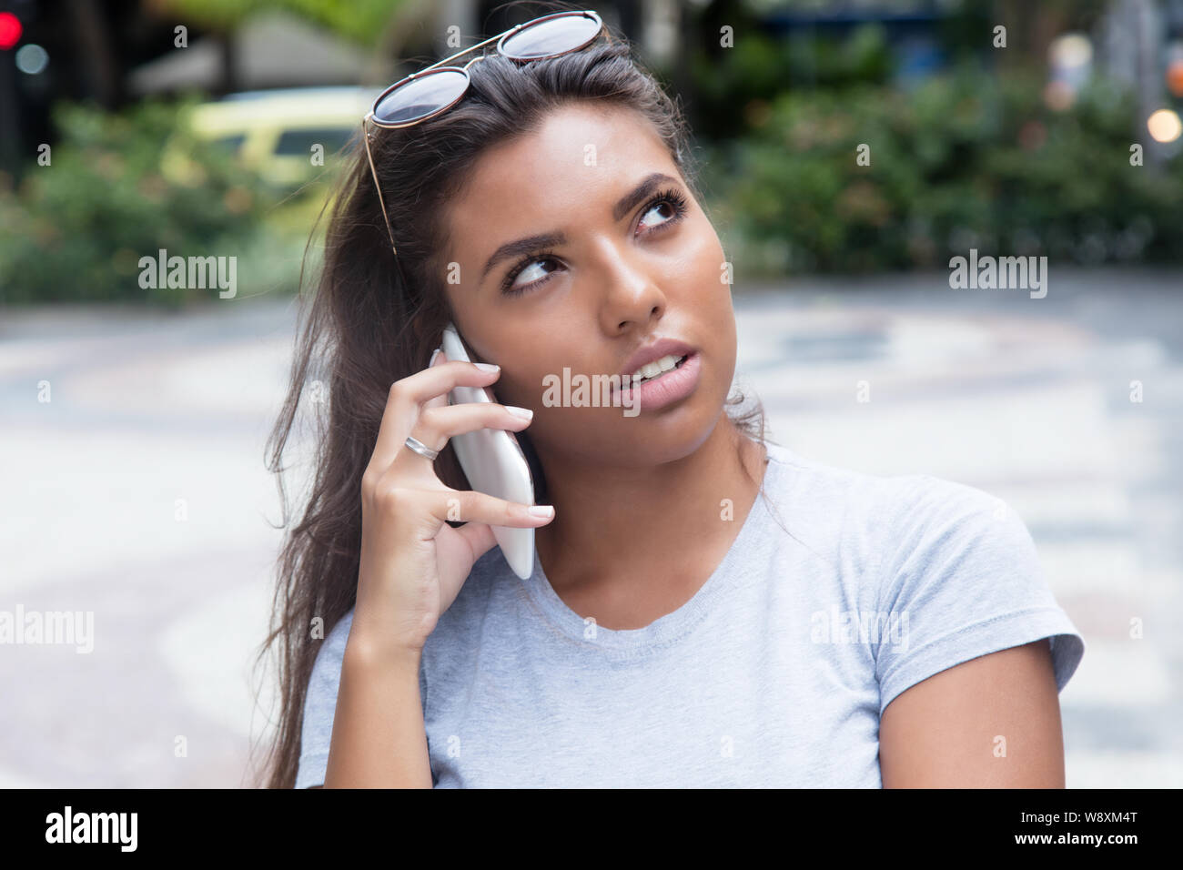 Latin female teenager listening at smart phone outdoor in the summer in the city Stock Photo