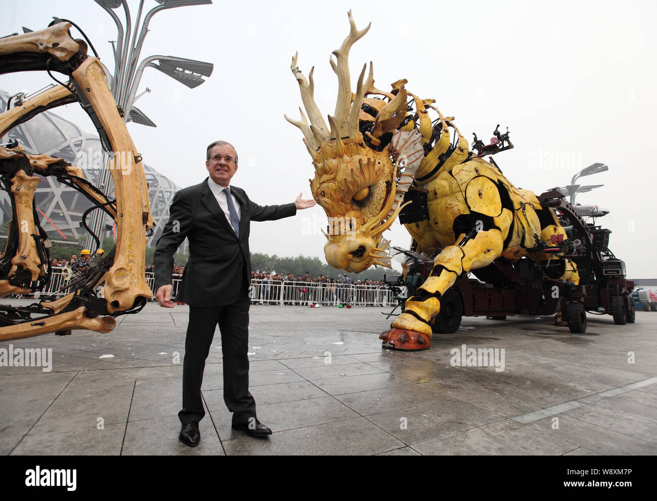French Ambassador to China Maurice Gourdault-Montagne shows the horse-dragon sculpture, right, in front of the Bird's Nest Stadium at the Olympic Gree Stock Photo