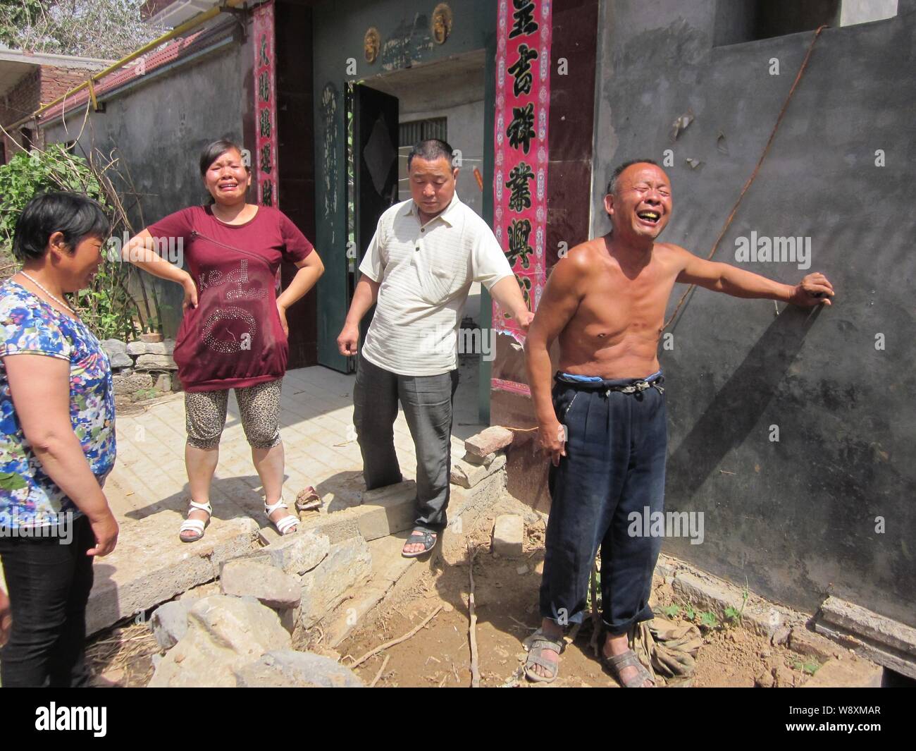 The villager, right, whose wife and son died after they fell into an open pit toilet cries next to the cesspit at the Cuizhuang Village, Xinxiang city Stock Photo
