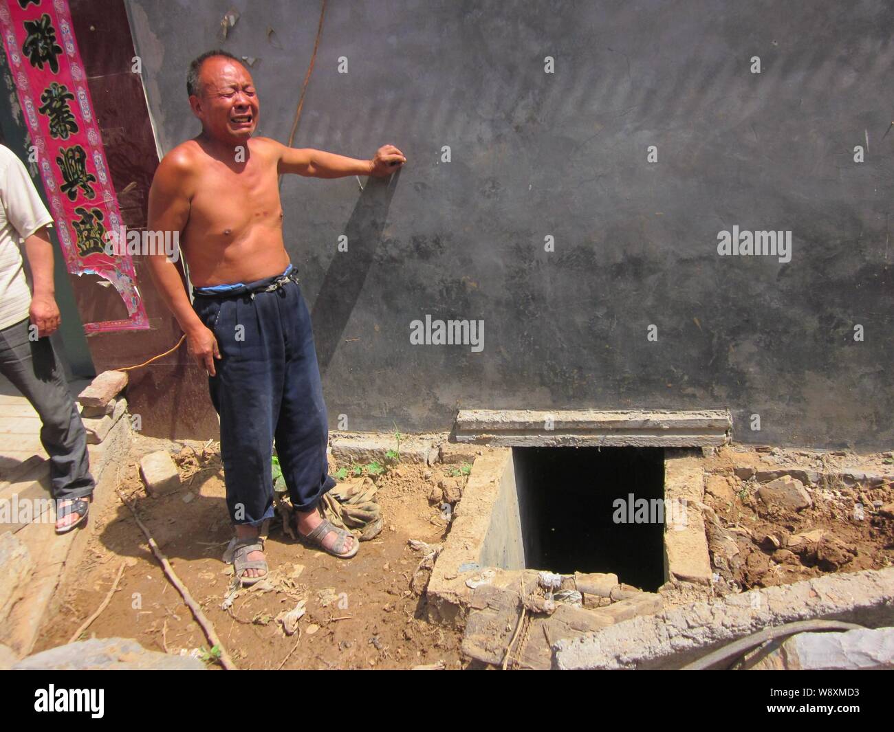 The villager whose wife and son died after they fell into an open pit toilet cries next to the cesspit at the Cuizhuang Village, Xinxiang city, centra Stock Photo