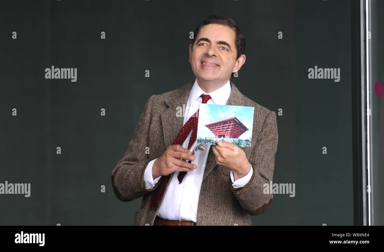 English actor Rowan Atkinson shows a photo of China pavilion as he plays Mr. Bean during a filming session for a TV commercial at the Mercedes-Benz Ar Stock Photo