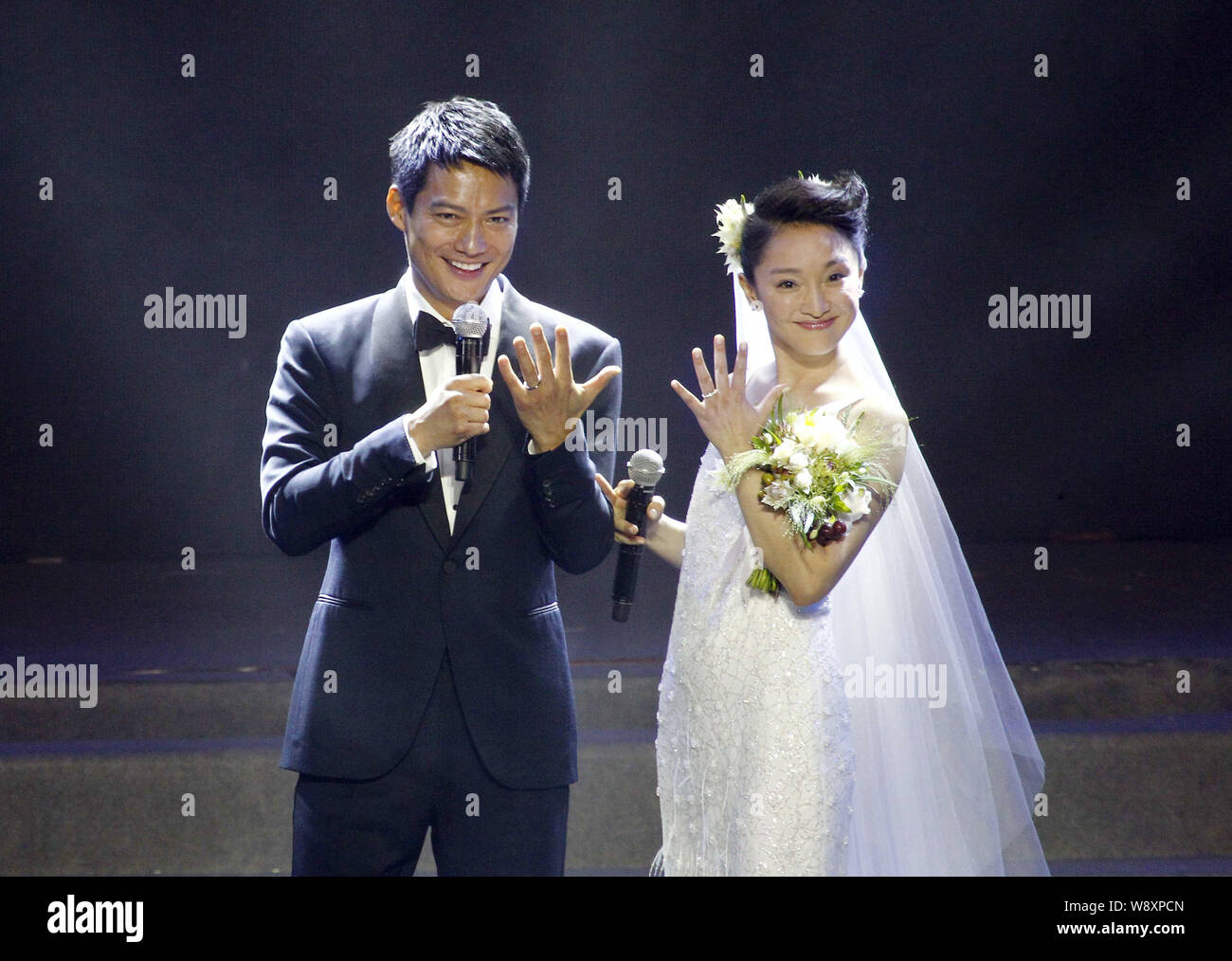 American actor Archie Kao, left, and Chinese actress Zhou Xun in a white wedding dress show their engagement rings after announcing their wedding duri Stock Photo