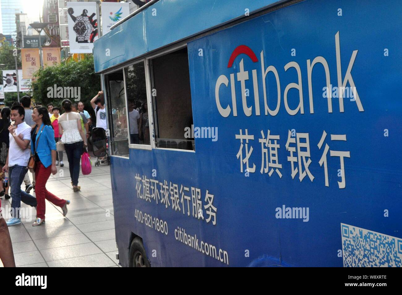 --FILE--Pedestrians walk past a sightseeing car with an advertisement for Citibank of Citigroup on the Nanjing Road shopping street in Shanghai, China Stock Photo
