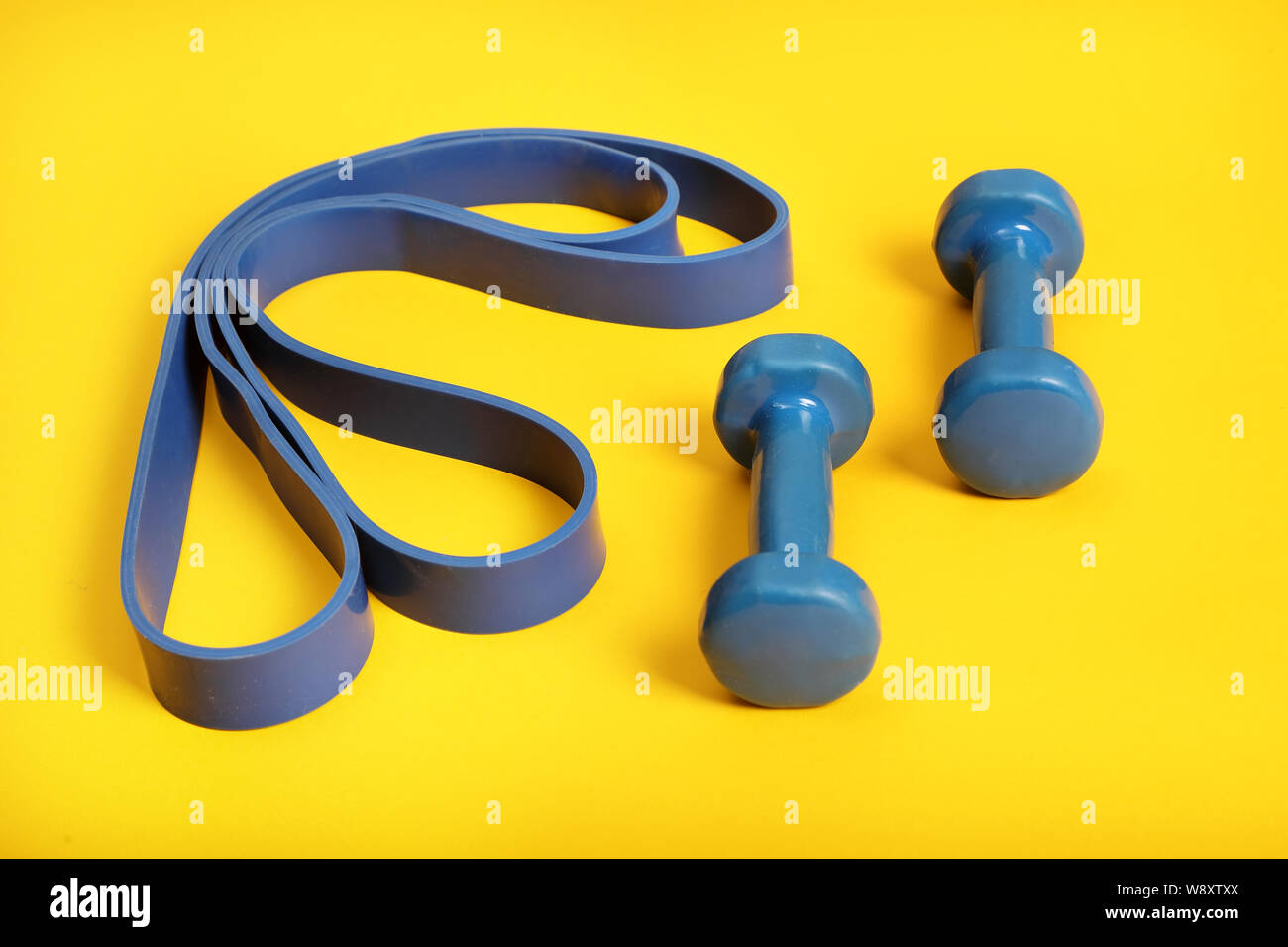 light weight dumbbells and a blue exercise resistance band on a bright