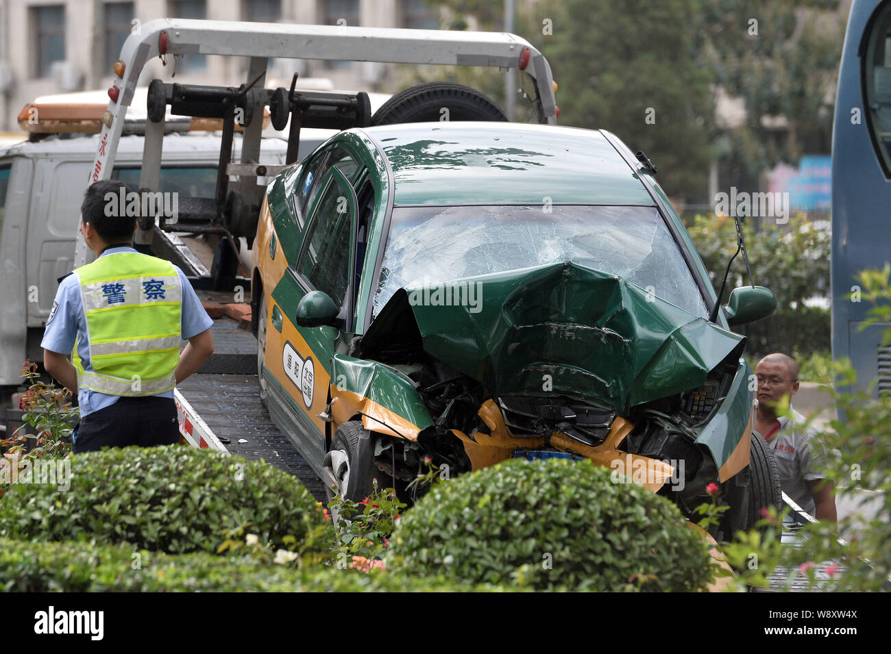 The damaged taxi is loaded onto a trailer after it crashed into a tree, killing 3 people, on the Third Ring Road in Beijing, China, 24 August 2014. Stock Photo