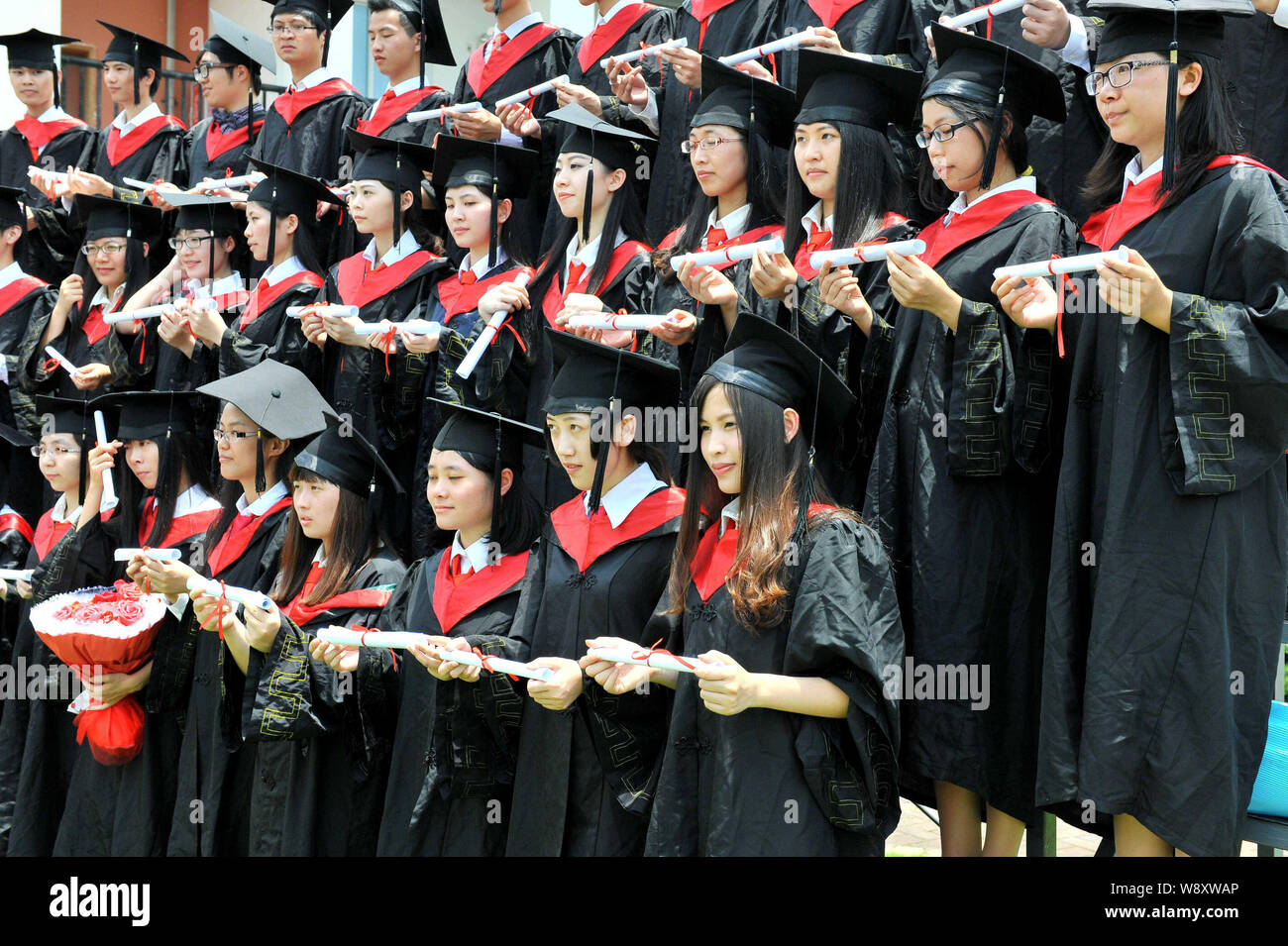 --FILE--Chinese graduates dressed in academic gowns and hats pose with their diplomas at Sun Yat-sen University in Guangzhou city, south Chinas Guangd Stock Photo
