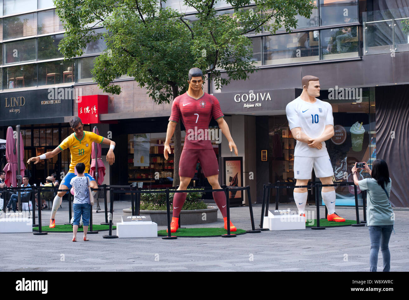 Visitors take photos of three giant figures of football superstars (from left) Neymar of Brazil, Cristiano Ronaldo of Portugal and Wayne Rooney of Eng Stock Photo