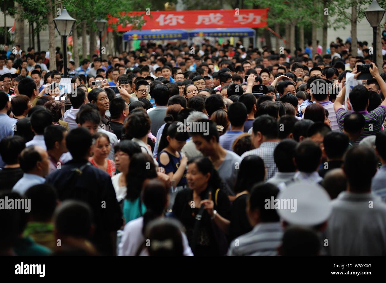 A crowd of Chinese parents, front, wait at the gate of a school for their children after they finished the first examination of the national college e Stock Photo