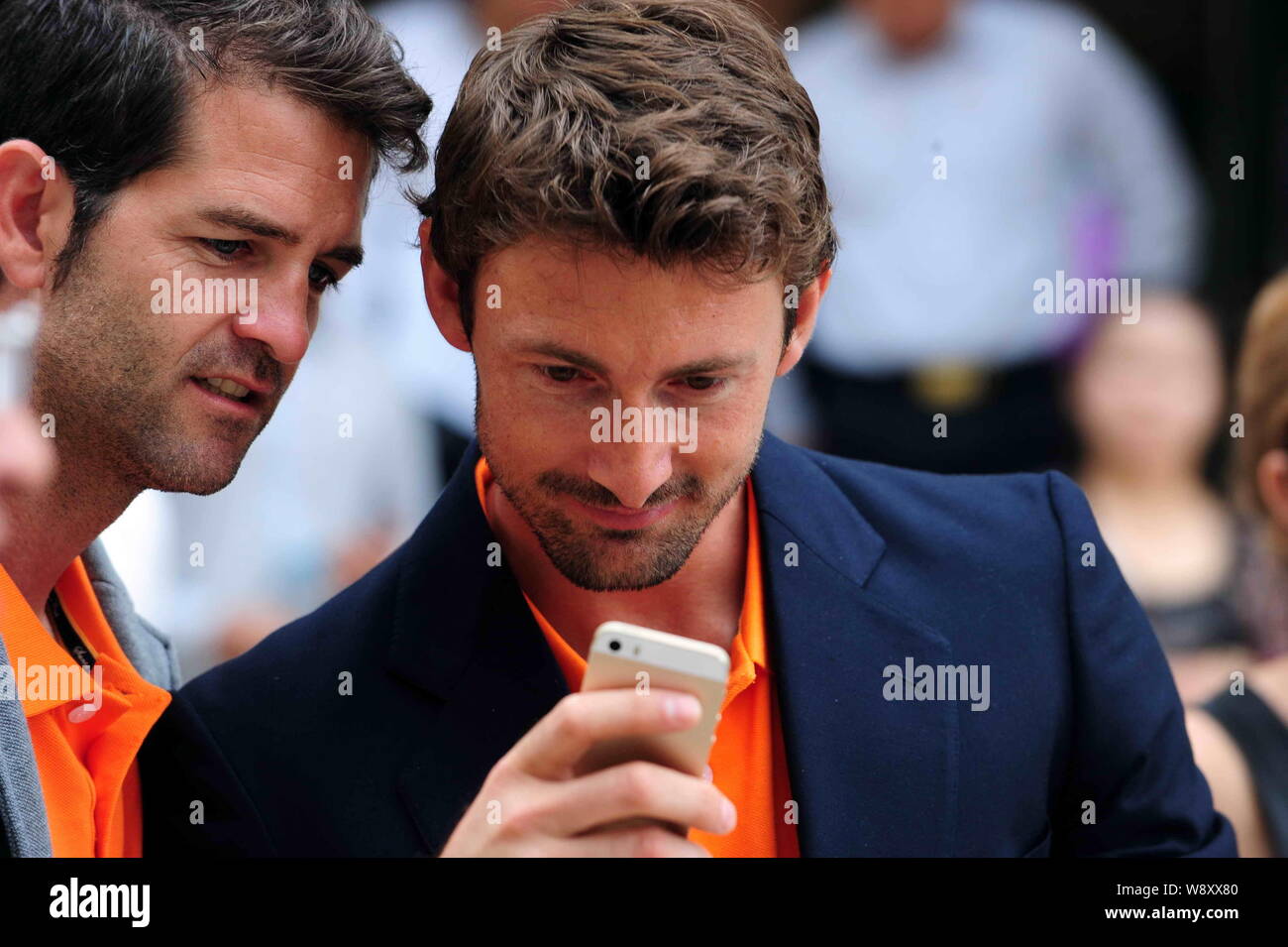 Spanish tennis player Juan Carlos Ferrero, right, uses an Apple iPhone 5S smartphone during the launch ceremony for Grand Gemdale-JC Ferrero Internati Stock Photo