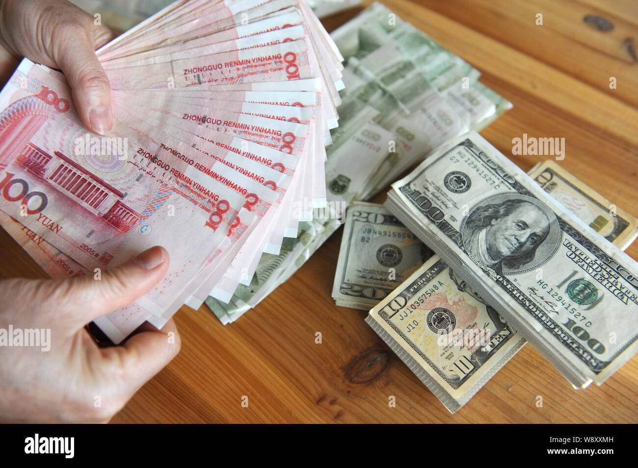 FILE--A Chinese resident counts his RMB (renminbi) yuan and US dollar  banknotes in Qionghai city, south Chinas Hainan province, 27 February 2014  Stock Photo - Alamy