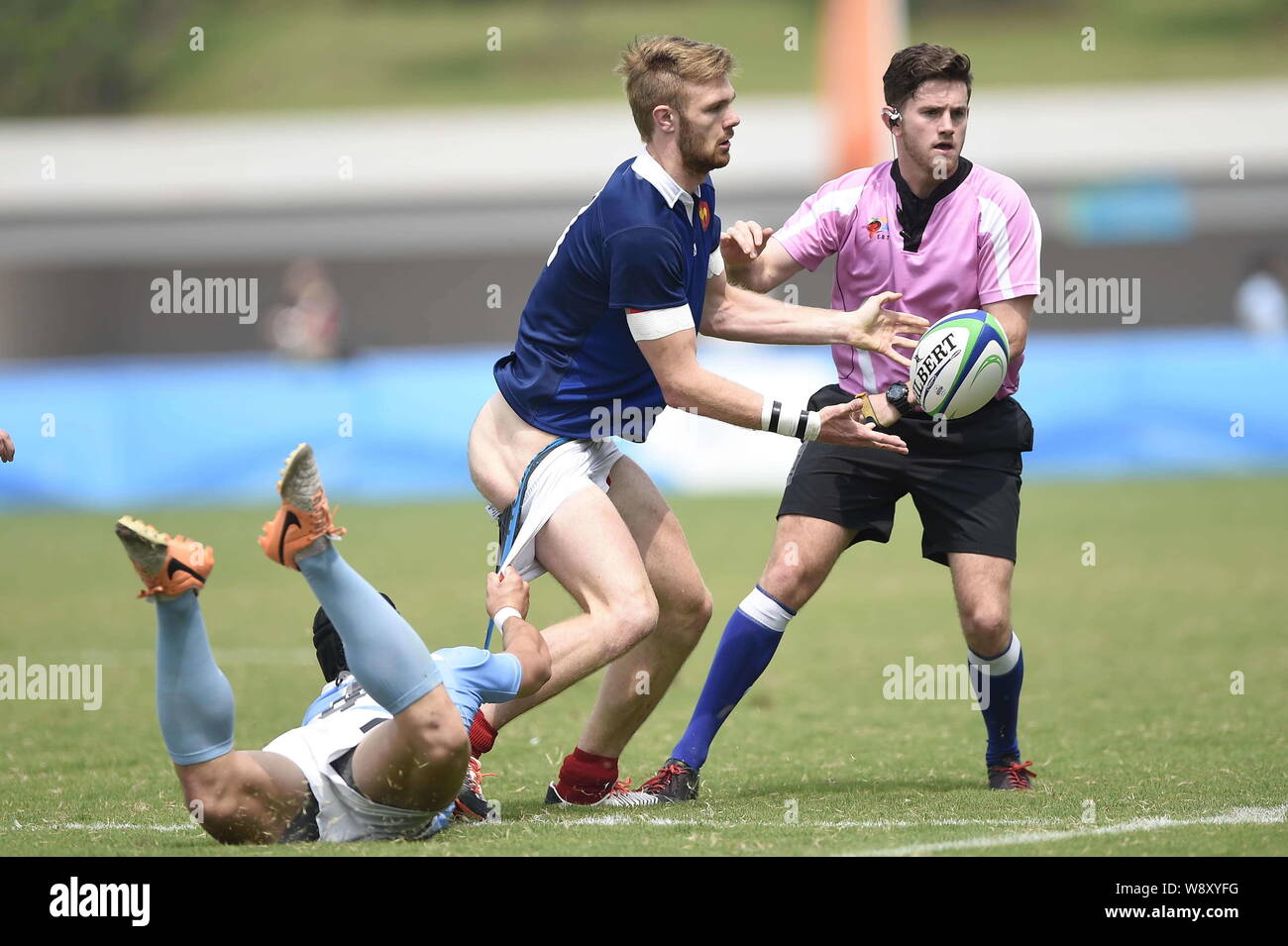 Juan Ignacio Conil Vila of Argentina, left, pulls down the shorts of Sacha Valleau of France, center, at the Rugby Sevens final during the 2014 Summer Stock Photo