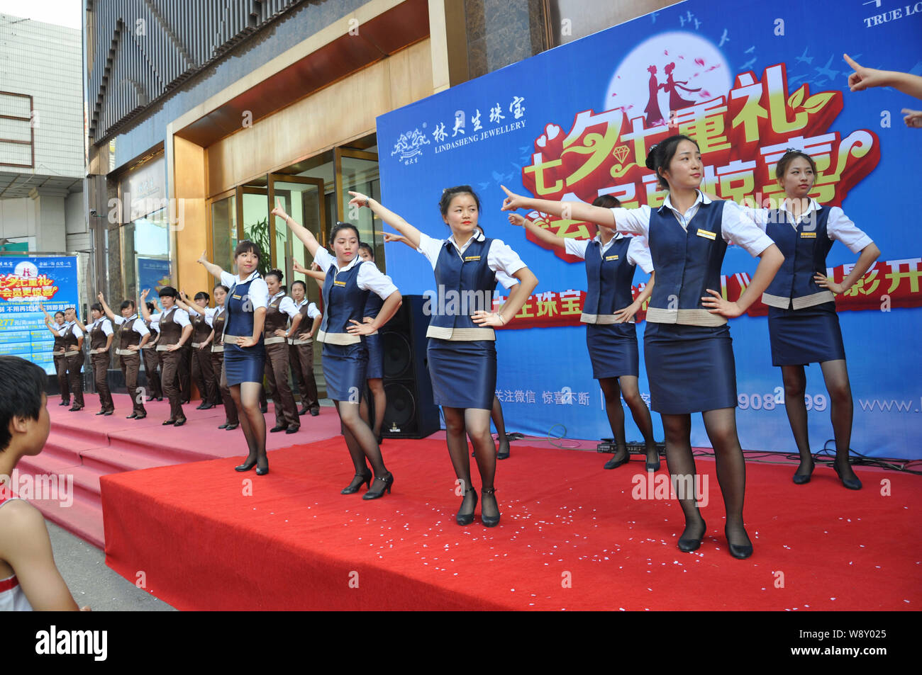--FILE--Chinese employees dressed in uniforms dance to the music of Little Apple in front of a store in Shenyang city, northeast Chinas Liaoning provi Stock Photo