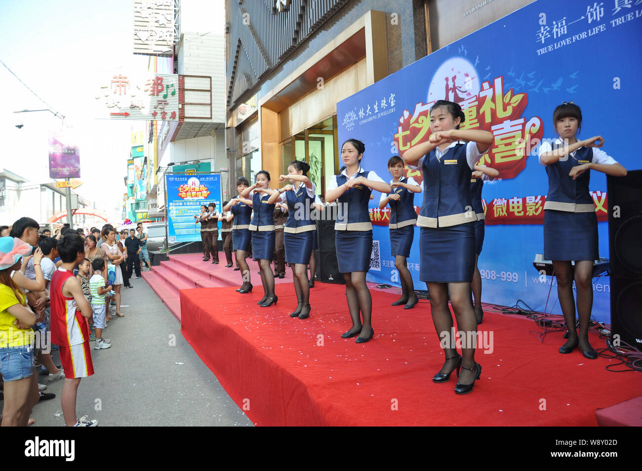 --FILE--Chinese employees dressed in uniforms dance to the music of Little Apple in front of a store in Shenyang city, northeast Chinas Liaoning provi Stock Photo