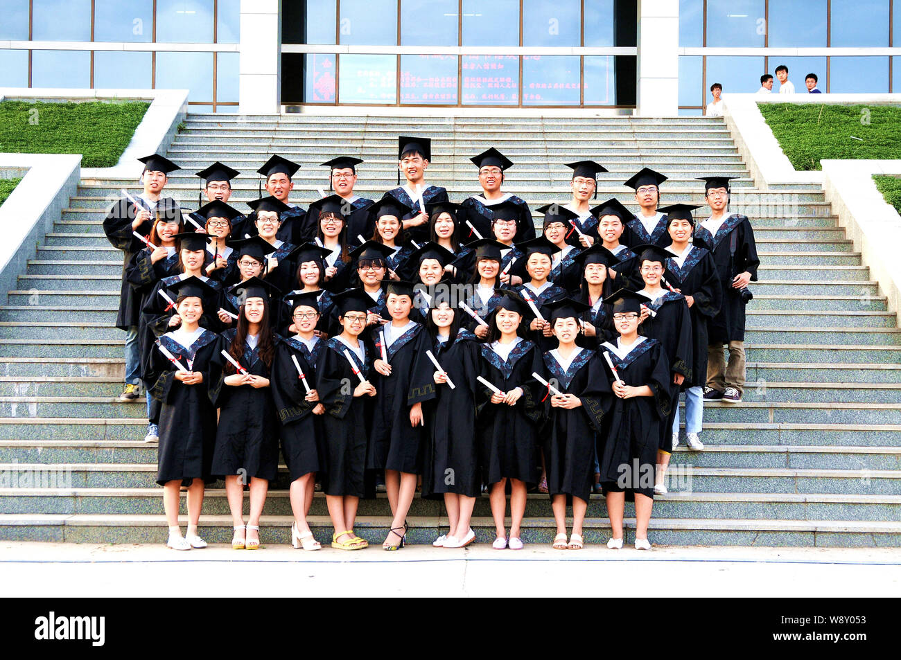 --FILE--Chinese graduates dressed in academic gowns and hats pose with their diplomas at Shandong Liaocheng University in Liaocheng city, east Chinas Stock Photo