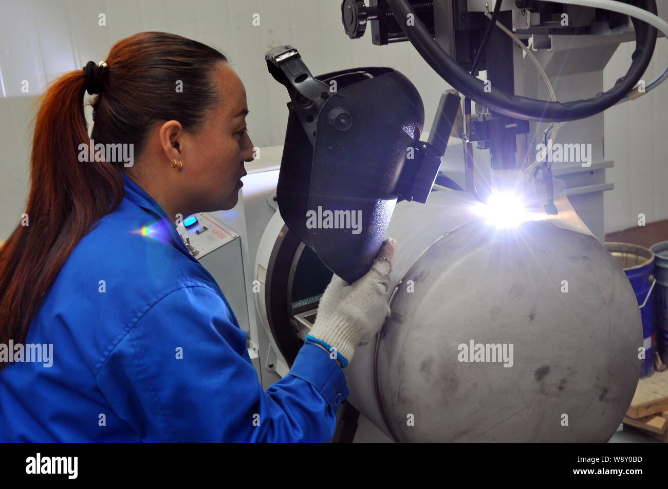--FILE--A female Chinese worker welds an LNG (Liquified Natural Gas) cylinder at the plant of Rizhao Xingye Auto Fittings Co., Ltd. in Rizhao city, ea Stock Photo