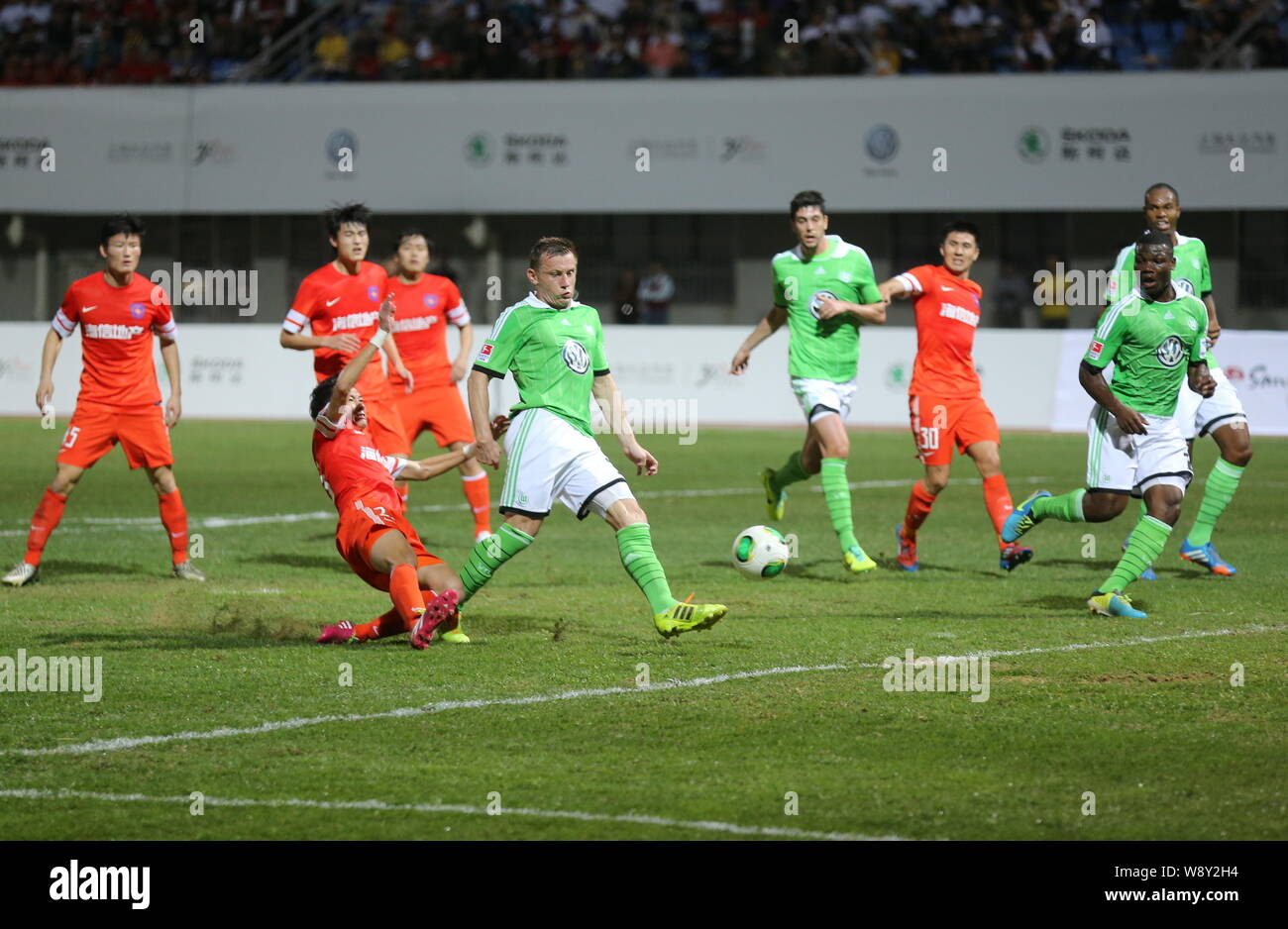 Ivica Olic of Germanys VfL Wolfsburg, center, plays a shot against Chinas Qingdao Jonoon in a soccer friendly match in Qingdao city, east Chinas Shand Stock Photo