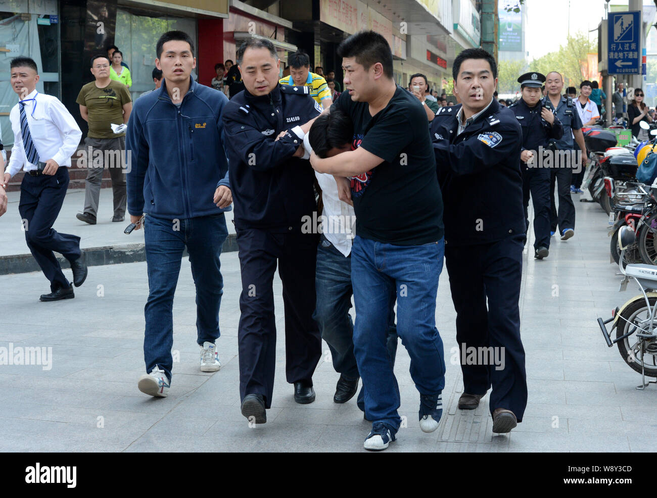 Chinese police officers arrest a knifewielding man, center in white
