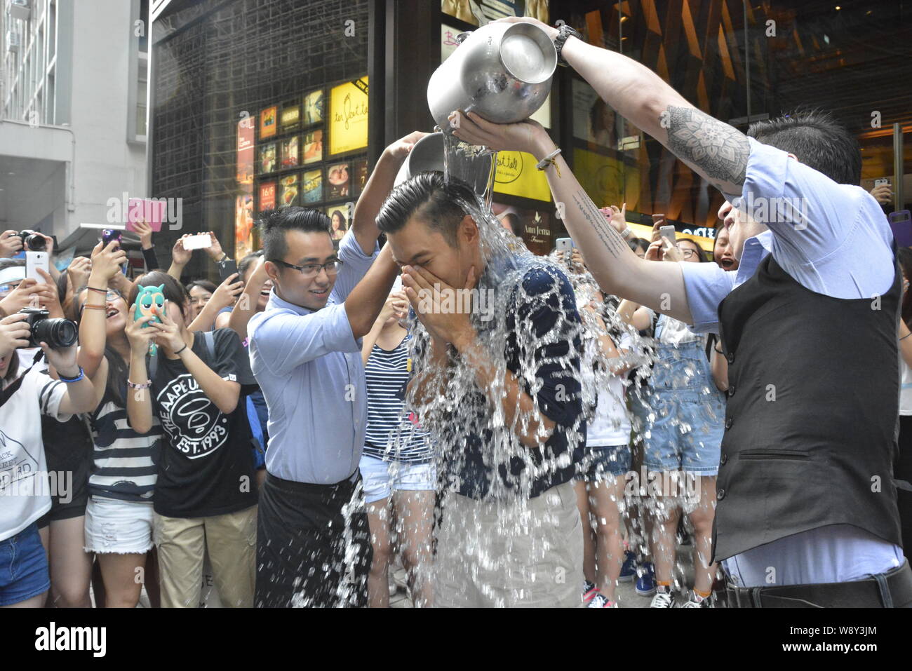 Choi Siwon of South Korean pop group Super Junior, second right, braves the Ice Bucket Challenge in Central, Hong Kong, China, 18 August 2014. Stock Photo