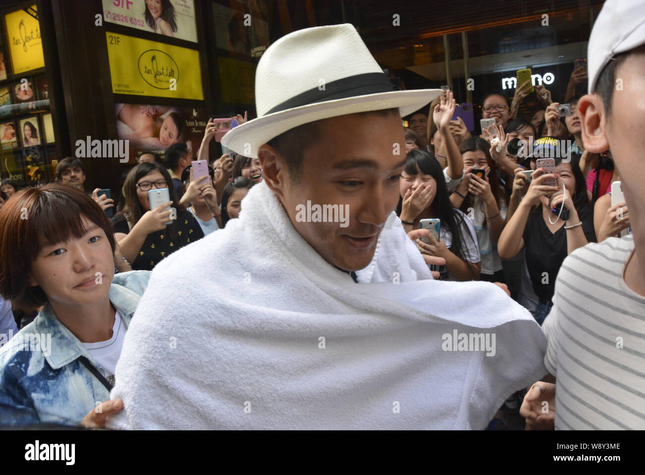 Choi Siwon of South Korean pop group Super Junior, center, is wrapped up with a towel after braving the Ice Bucket Challenge in Central, Hong Kong, Ch Stock Photo