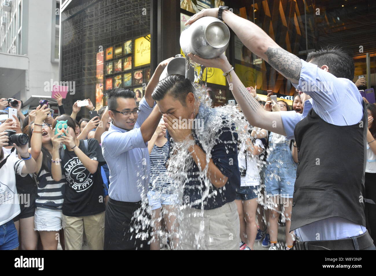 Choi Siwon of South Korean pop group Super Junior, second right, braves the Ice Bucket Challenge in Central, Hong Kong, China, 18 August 2014. Stock Photo
