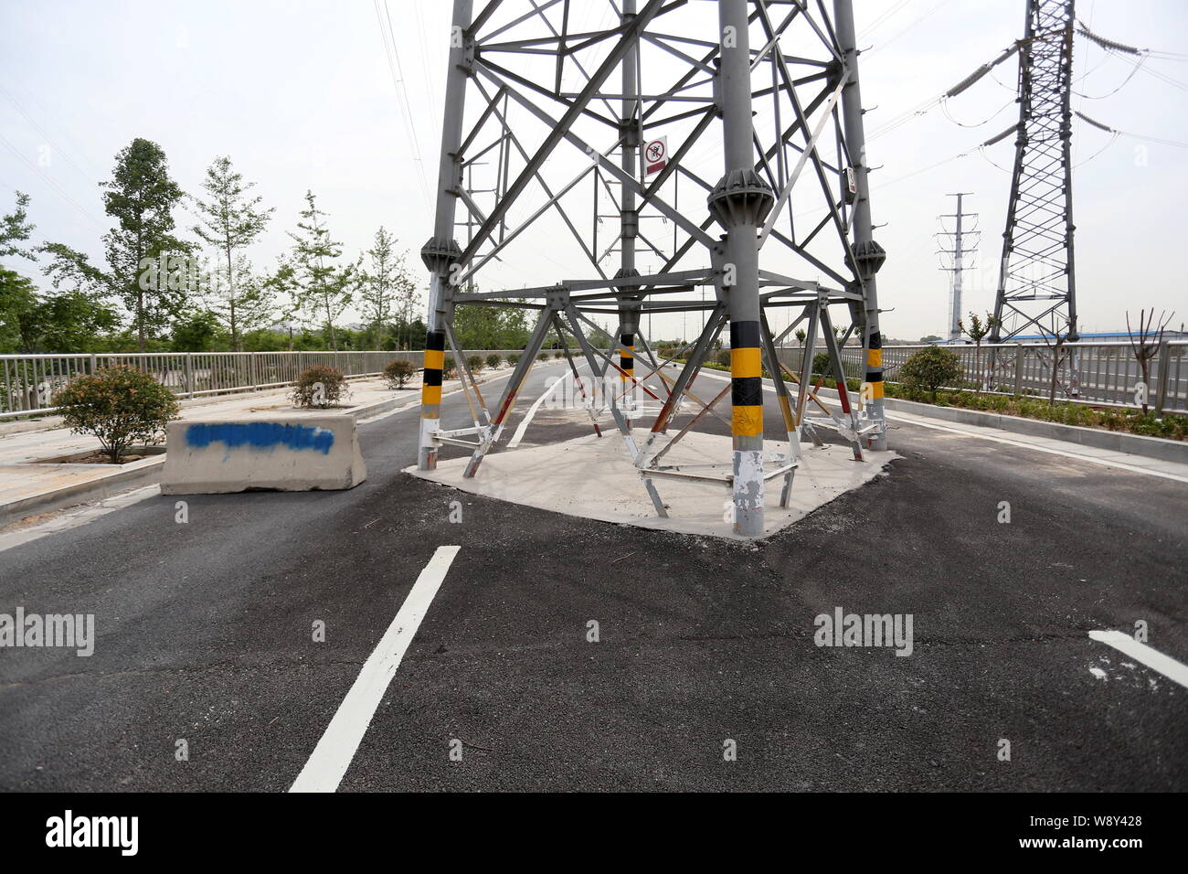 A pylon bearing electric wires is pictured in the middle of a newly-built highway in Zhengzhou city, central Chinas Henan province, 15 May 2014.   The Stock Photo