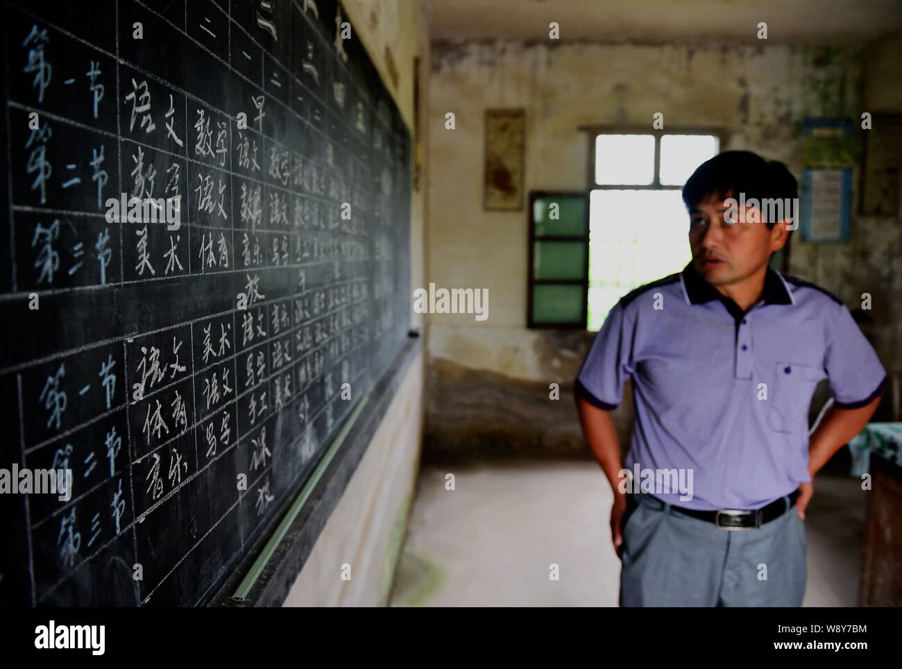 Chinese teacher Xie Daoyu checks curriculum schedules on the blackboard in the classroom at the Sanhe Primary School in Bailong town, Feidong county, Stock Photo