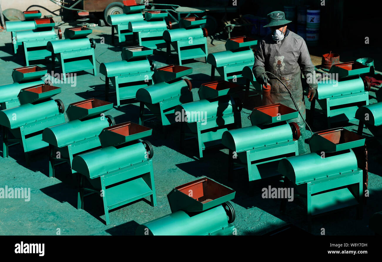 --FILE--A Chinese worker spray-paints cultivators at a factory in Zouping county, east Chinas Shandong province, 12 November 2014.     China's manufac Stock Photo