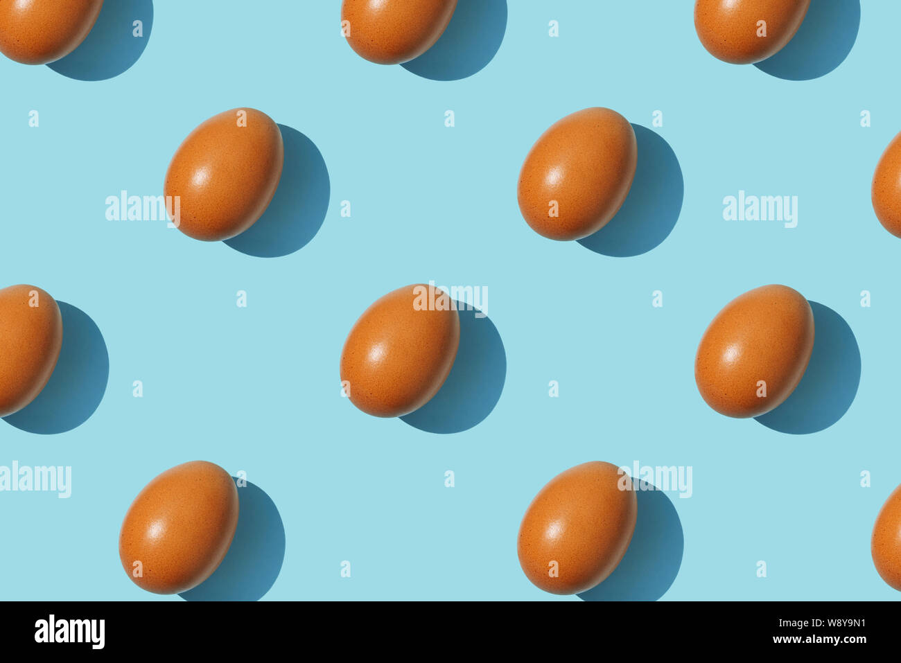 Brown eggs pattern on blue background. Creative layout. Top view. Stock Photo