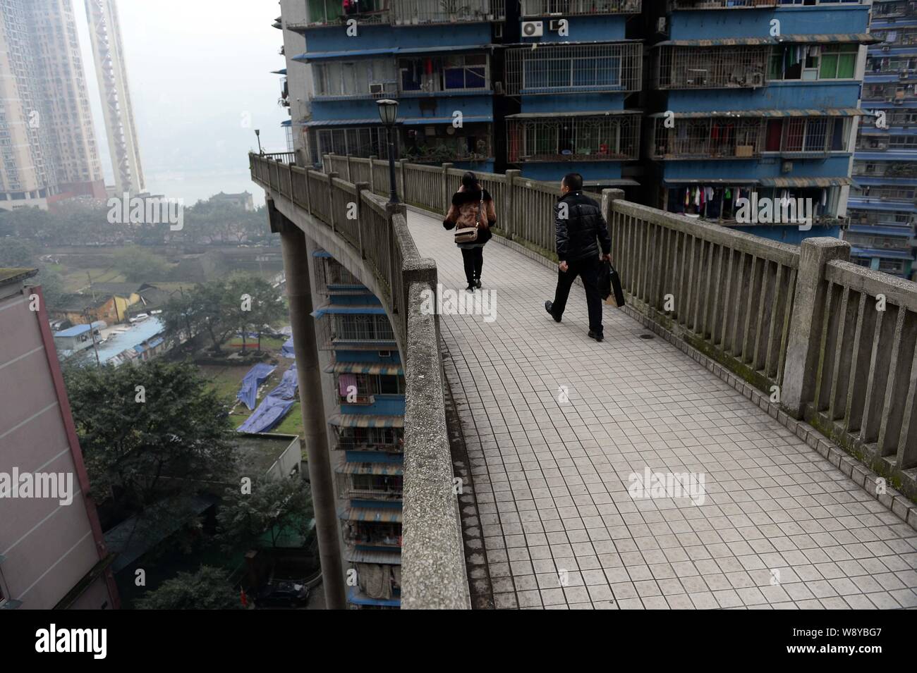 Local Chinese residents walk on the pedestrian bridge linking the 13th floor of a building with the street below in Chongqing, China, 14 December 2014 Stock Photo