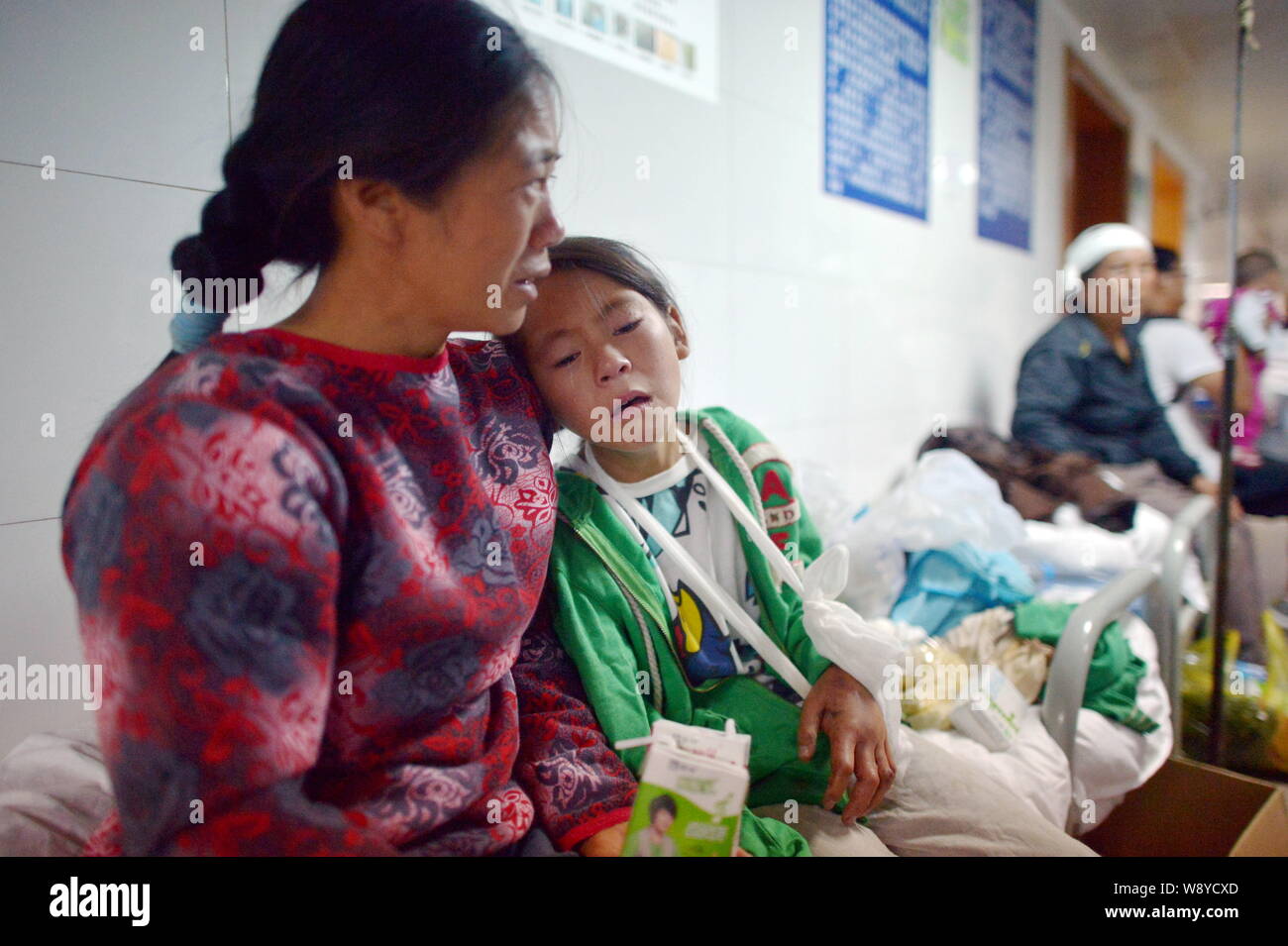 Chinese girl Yang Zhengqiao, second left, who lost her elder brother in the 6.5-magnitude earthquake weeps with her mother at the Ludian Peoples Hospi Stock Photo