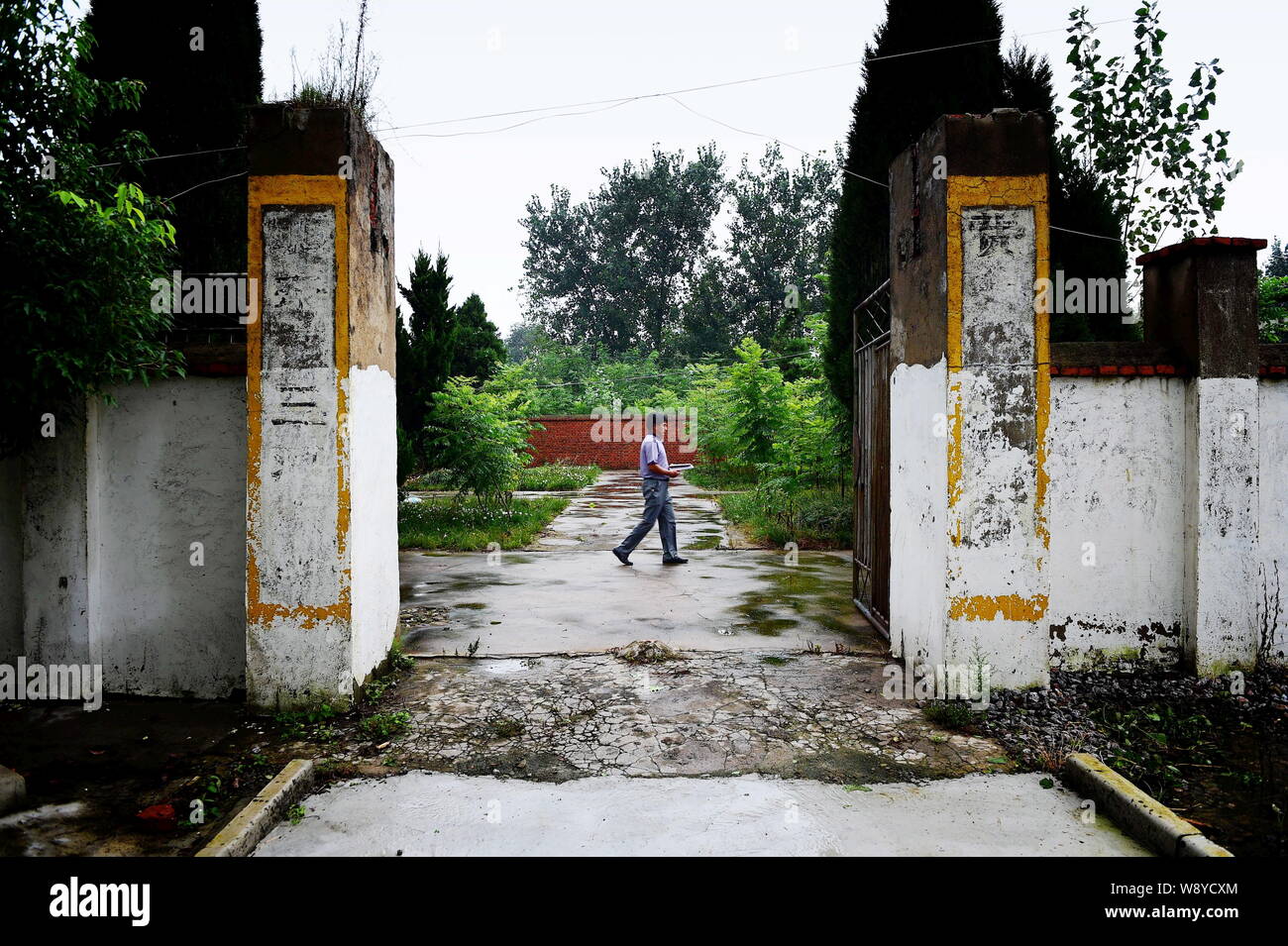 Chinese teacher Xie Daoyu walks past the gate of the Sanhe Primary School in Bailong town, Feidong county, Hefei city, east China's Anhui province, 31 Stock Photo