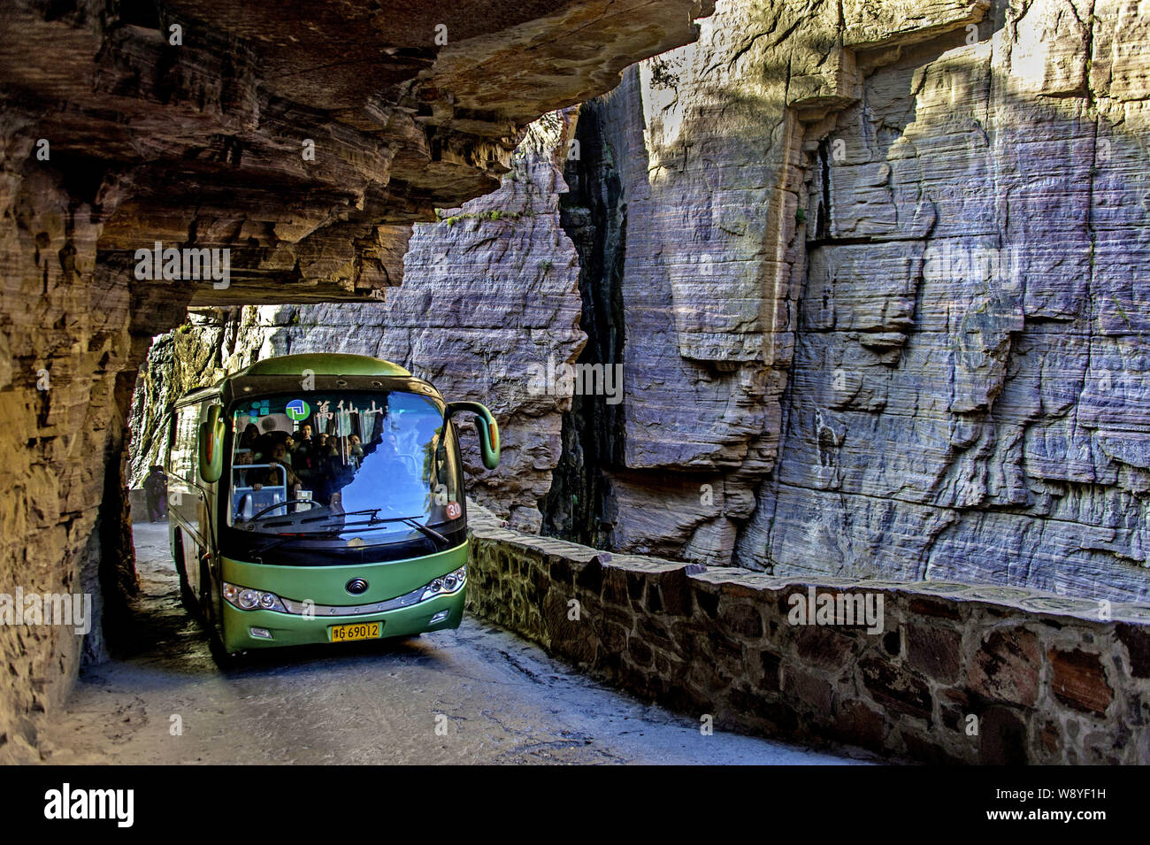 A tourist bus travels along the Guoliang Tunnel through the Wanxian Mountain in the Taihang Mountains in Huixian county, Xinxiang city, central China' Stock Photo