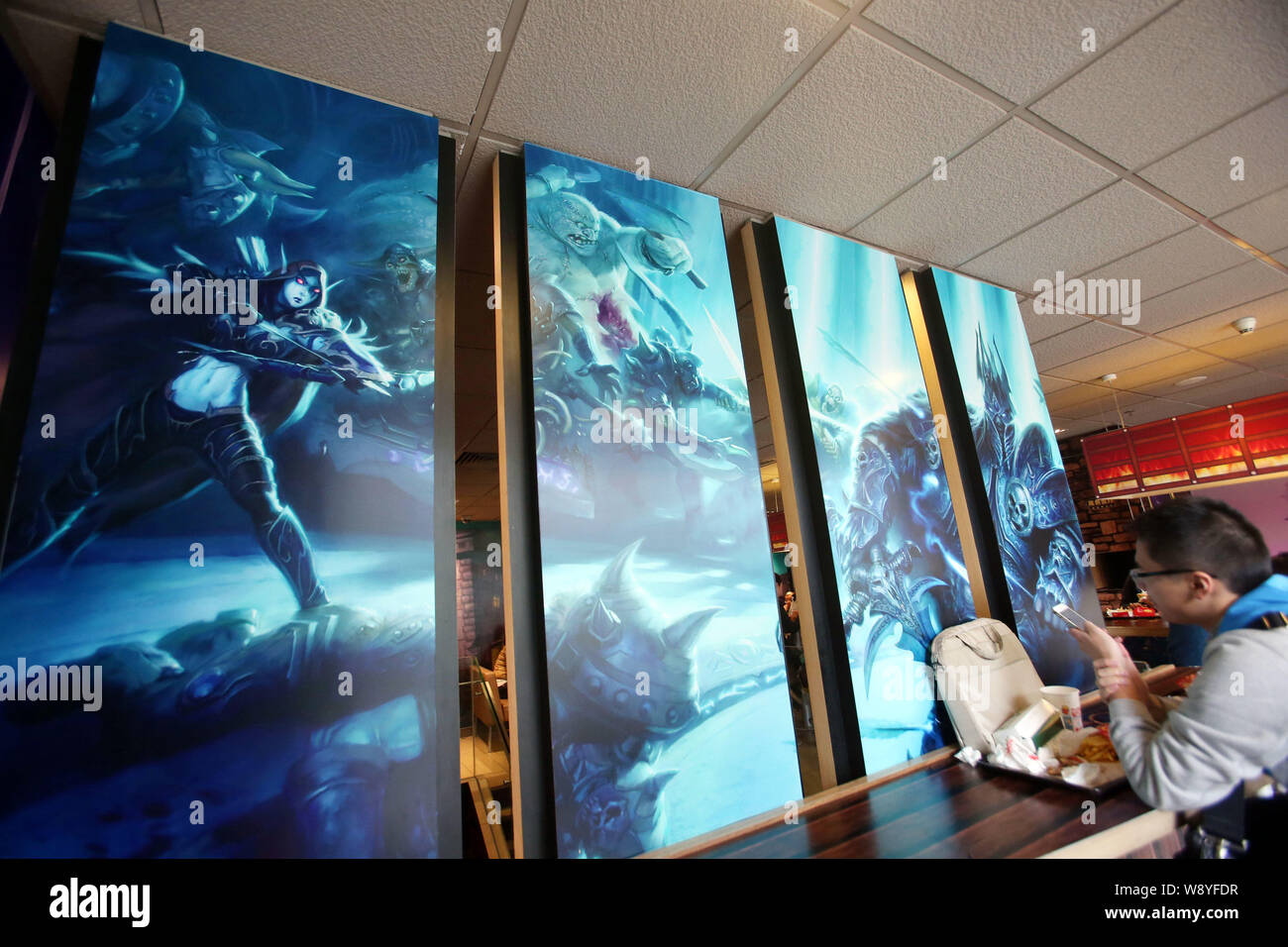 A customer uses his smartphone as he eats food at a WorldofWarcraftthemed fastfood