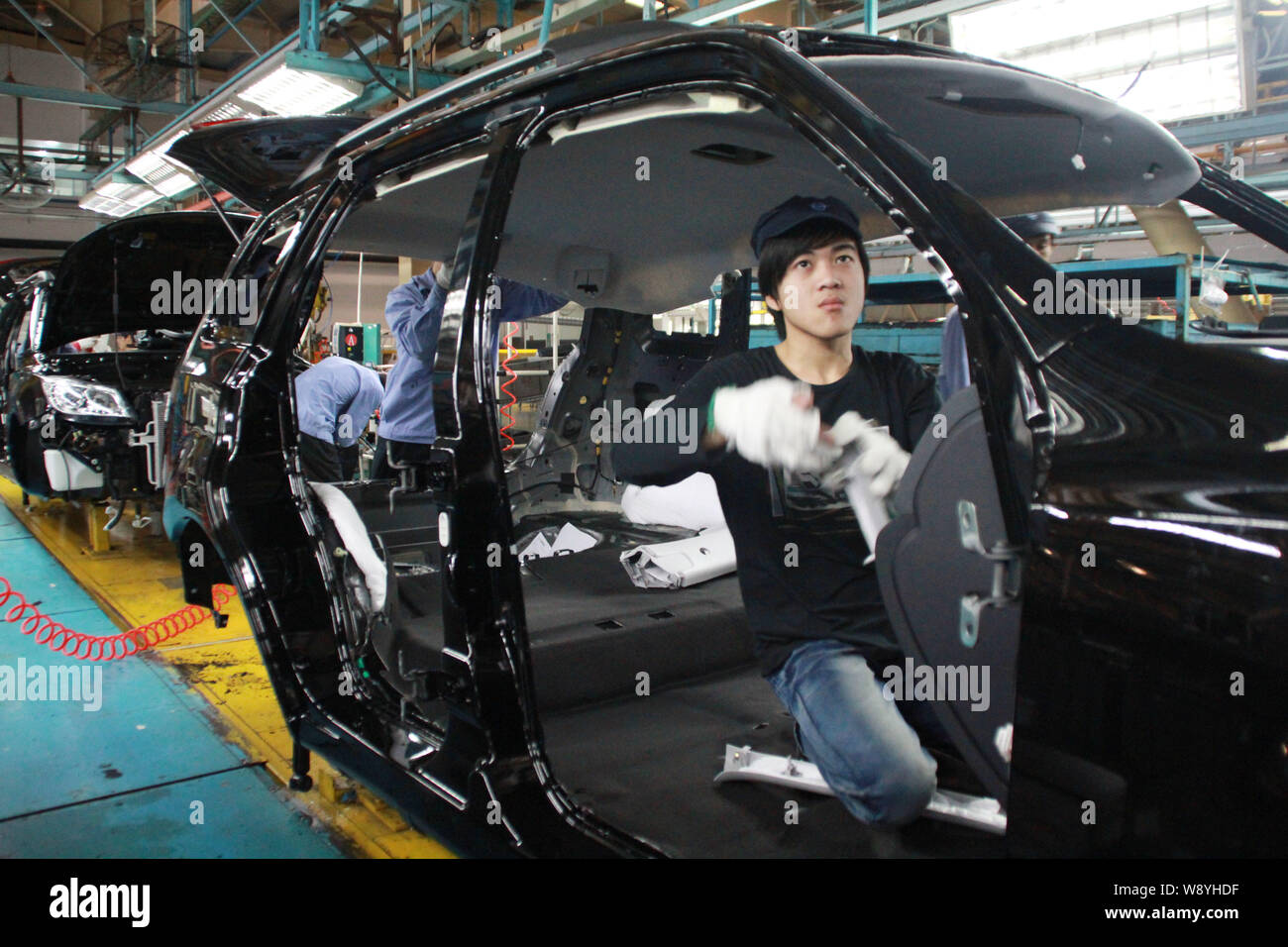 --FILE--A Chinese worker assembles a car on the assembly line at the auto plant of FAW Haima Automobile in Haikou city, south Chinas Hainan province, Stock Photo