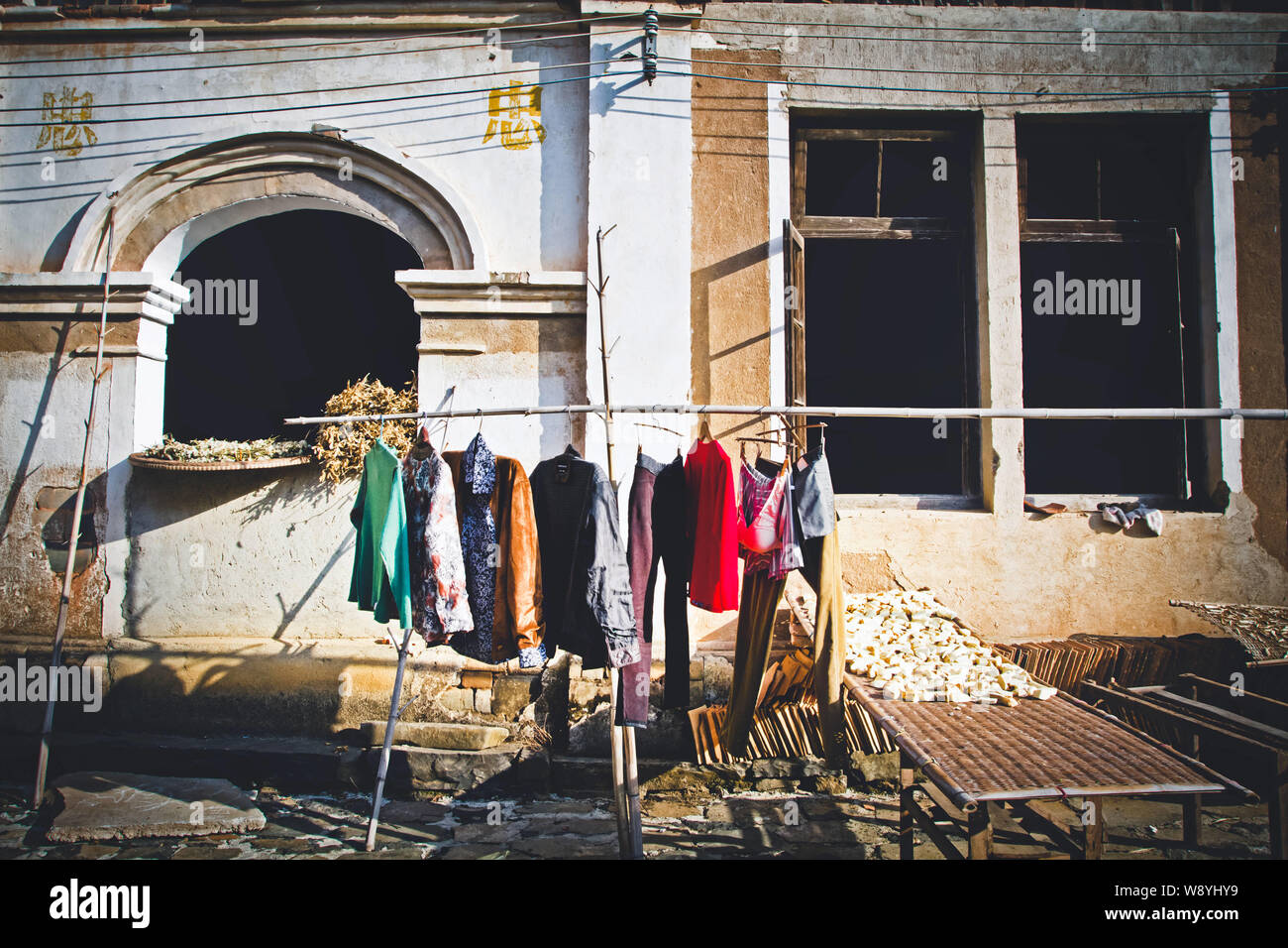 Local Chinese residents use a bamboo pole to air out clothes in front of a building in Heishi Village, PanAn county, east Chinas Zhejiang province, 23 Stock Photo