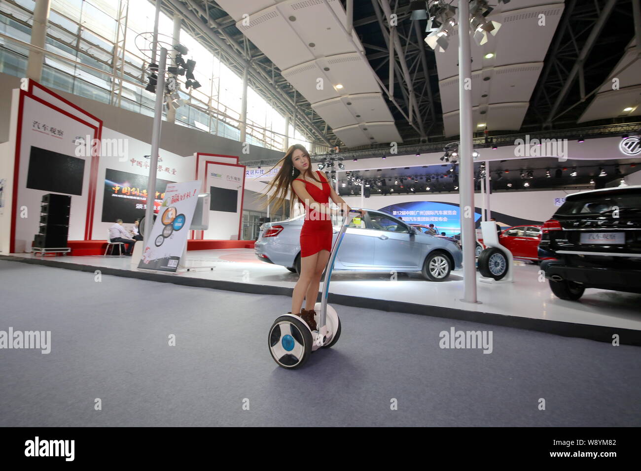 A model rides a two-wheeled Segway-like electric vehicle past the stand of Foton during the 12th China (Guangzhou) International Automobile Exhibition Stock Photo