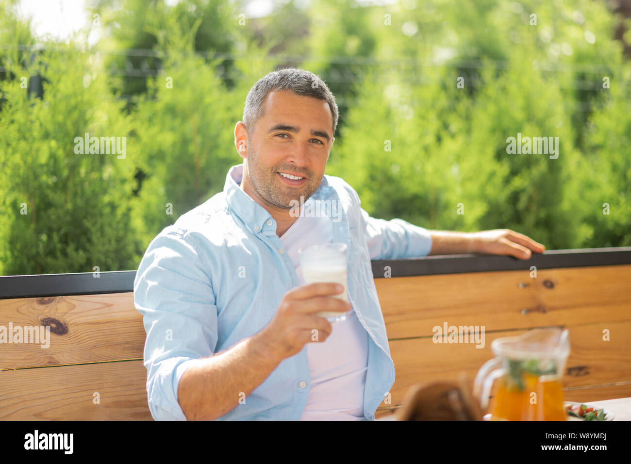 Handsome man smiling while having early meal outside Stock Photo