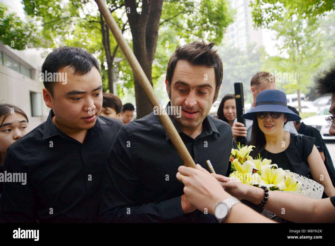 English snooker player Ronnie OSullivan, center, autographs for a fan as he arrives for a preparation for the upcoming World Snooker Shanghai Masters Stock Photo