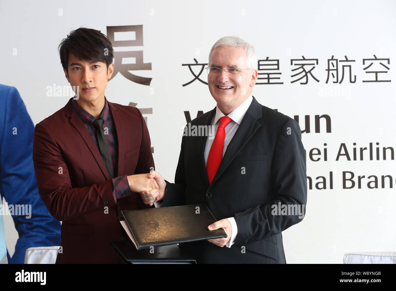Bruneian actor Wu Chun, left, shakes hands with Royal Brunei Airlines president Dermot Mannion during a signing ceremony for becoming the internationa Stock Photo