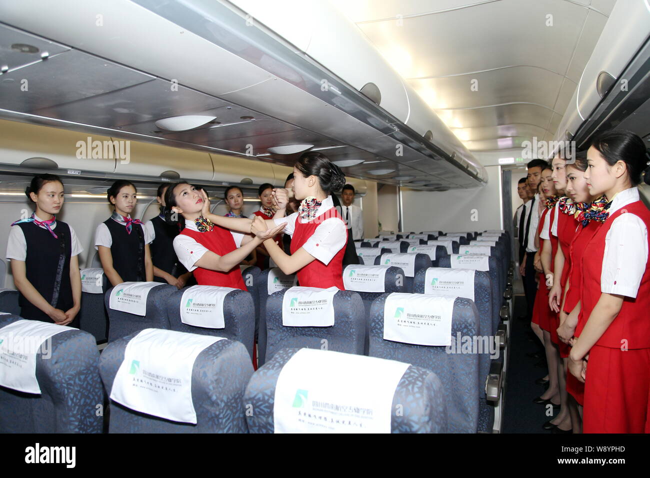 Young Chinese students dressed air hostess uniforms learn Wing Chun, a concept-based Chinese martial art, onboard a mock Airbus A330 cabin at Sichuan Stock Photo