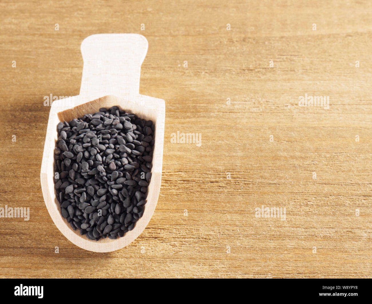 Black sesame (Sesamum indicum) in a scoop on a wooden background Stock Photo