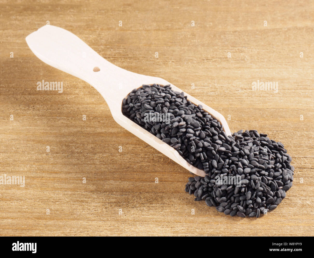 Black sesame (Sesamum indicum) in a scoop on a wooden background diagonally Stock Photo
