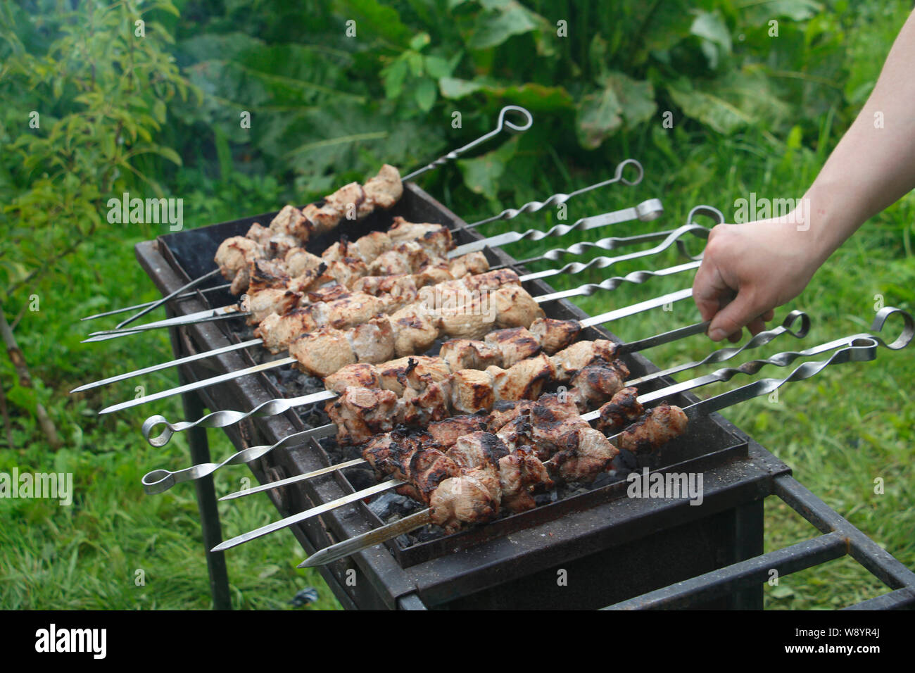 Cook cooks barbecue skewers. Marinated kebab is grilled on charcoal. Shish kebab barbecue was made of lamb, pork, beef, chicken. Roast beef skewers on Stock Photo