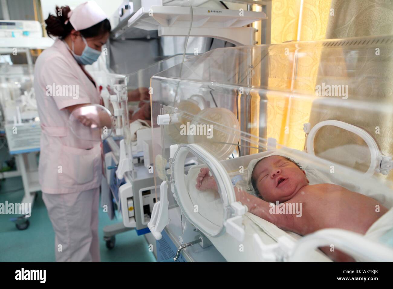 A Chinese nurse takes care of newborn babies in incubators at a