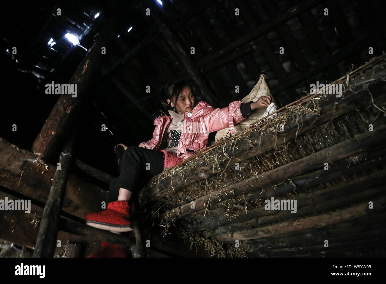 A young girl sits on the second floor of her shabby house in a poor village in Daliang Mountain in Liangshan Yi Autonomous Prefecture, southwest China Stock Photo