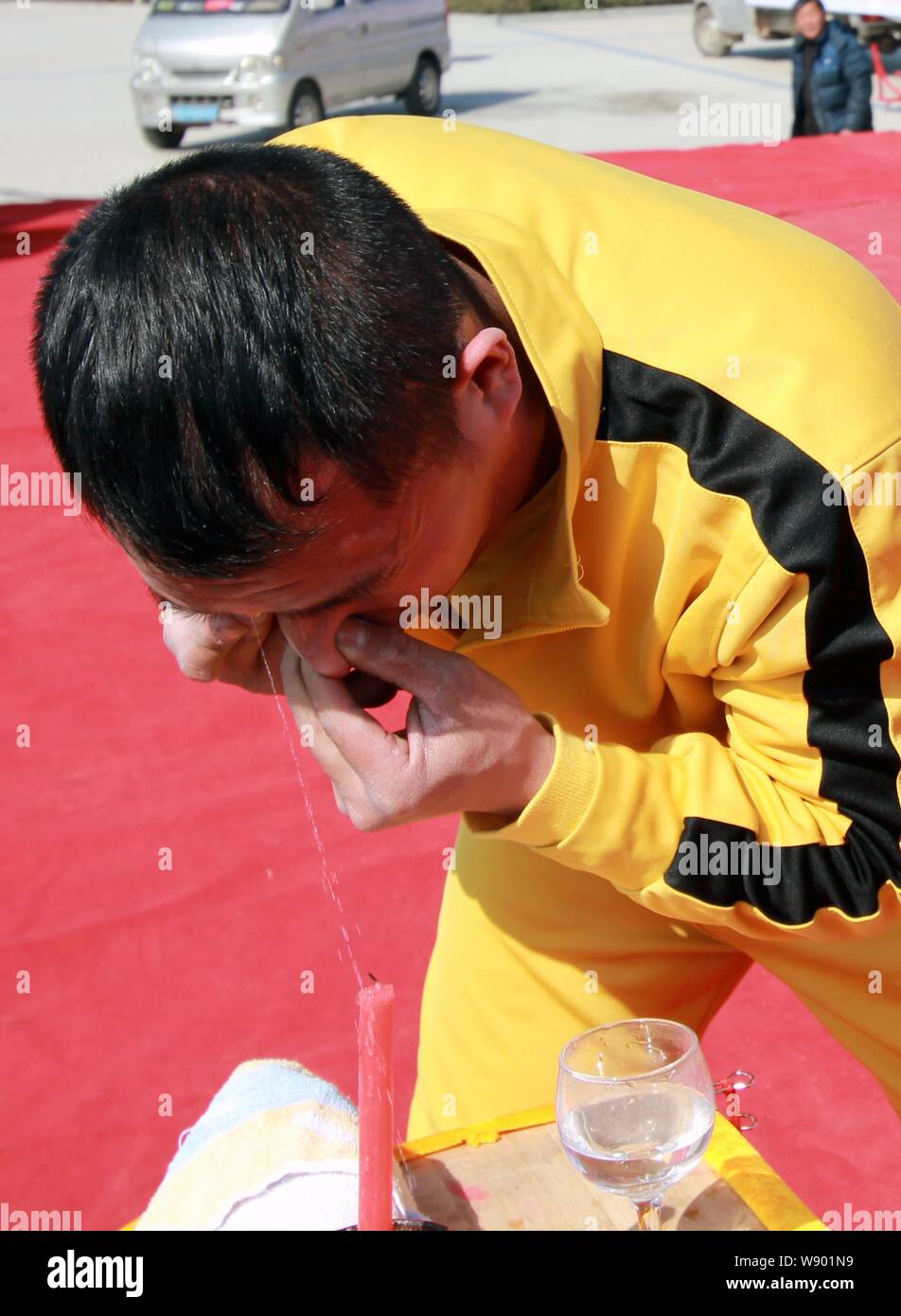 Zhang Yilong, a Chinese stunt performer dressed as Hong Kong action film star Bruce Lee, squirts water out of his right eye to put out a candle during Stock Photo