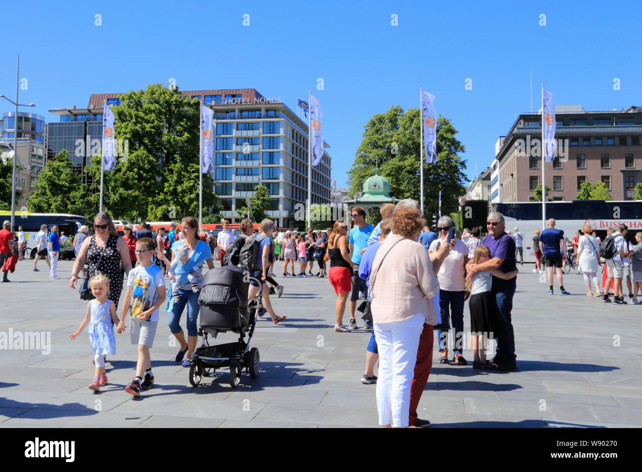 People crowd the public square, Festplassen, in Bergen, Norway, during the summer. Hotel Norge is seen in the background. Stock Photo