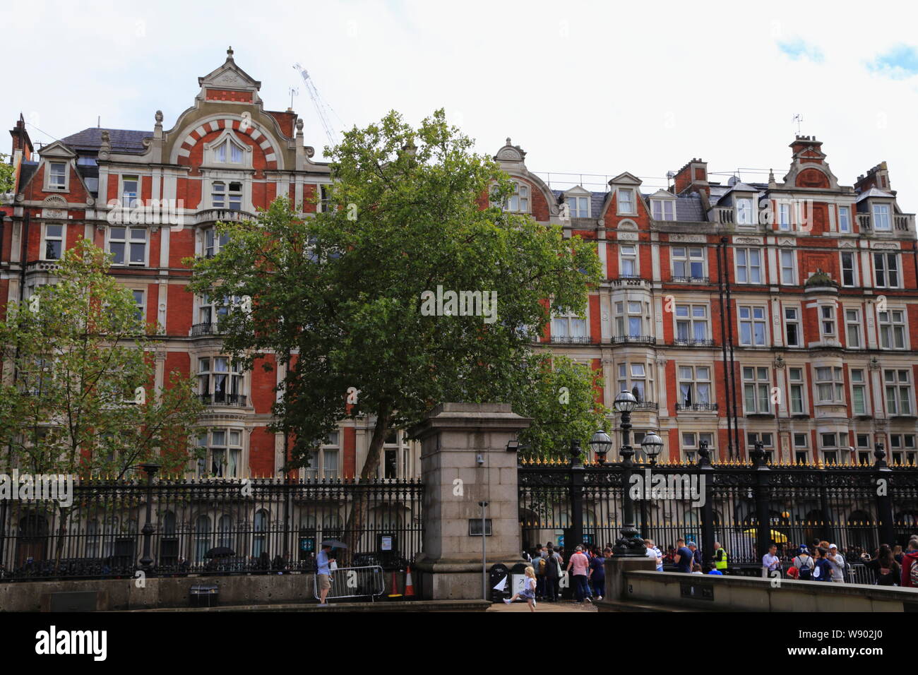 The facade of a red brick building opposite the British Museum, and people leaving the museum at the main gate in Bloomsbury, London, United Kingdom. Stock Photo