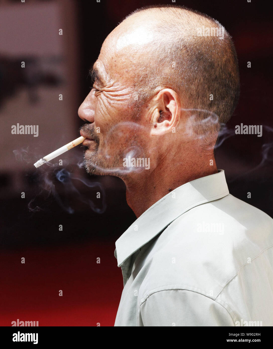 --FILE--A Chinese man smokes on a road in Yichang city, central Chinas Hubei province, 15 September 2013.   The head of the World Health Organisation Stock Photo