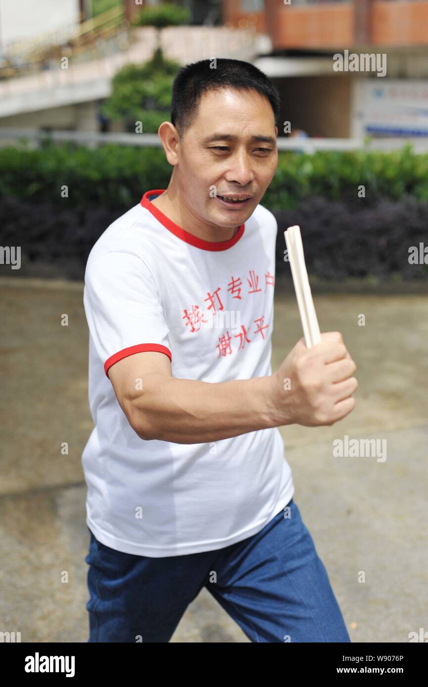 Xie Shuiping, who makes a living by offering himself as a punching bag, displays Qigong, a system of deep breathing exercises, on a street in Wuhan ci Stock Photo